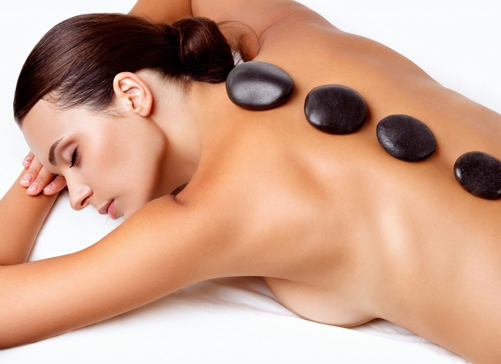 Stone Massage. Beautiful Woman Getting Spa Hot Stones Massage in Spa Salon.